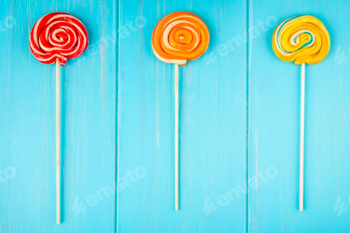 Preview: top view of colorful lollipops on a stick on blue wooden background