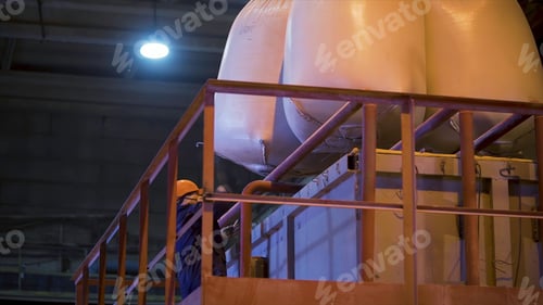 Preview: Worker at factory with bags for raw materials. Stock footage. Worker in hard hat opens suspended