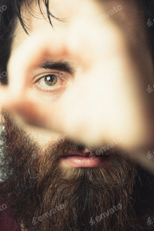 Preview: Super close up of an eye of a hipster man through his fingers