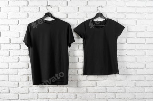 Preview: Black t-shirt hanging on a hanger against brick wall