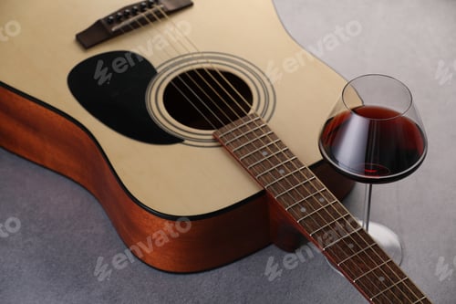 Preview: Acoustic guitar and red wine on grey table, closeup