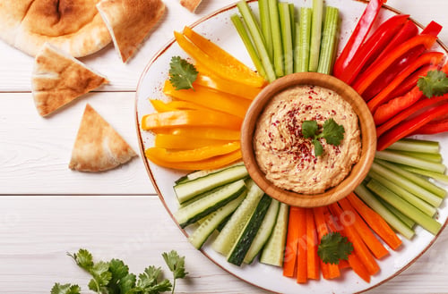 Vista previa: Homemade hummus with assorted fresh vegetables and pita bread.
