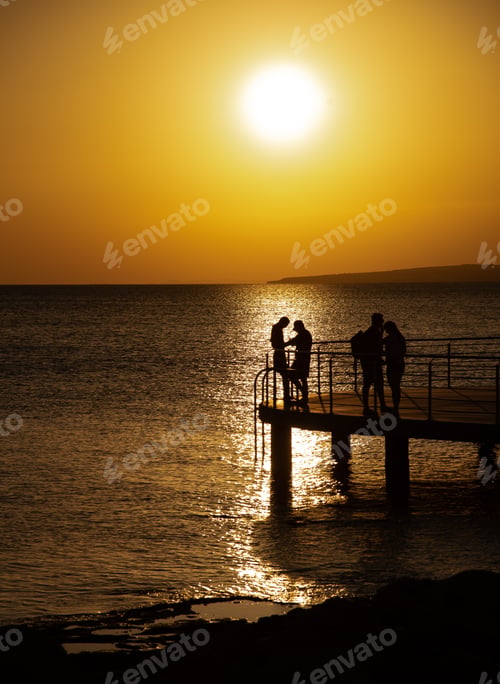 Preview: Silhouette of young couple enjoying beautiful sunset at beach. Romantic moment human relationship
