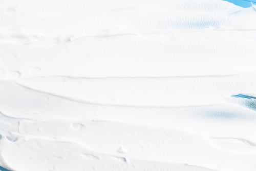 Preview: The texture of the face cream applied on a blue background with strokes.