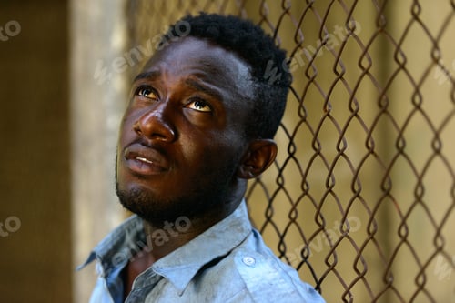 Preview: Face of young homeless African man looking up in the streets