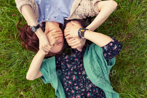 Preview: Top view of smiling friends lying on grass having fun