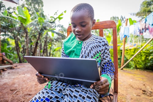 Preview: African young student sitting outdoors, keen on his tablet rehearsing his lessons