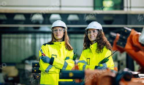 Preview: Skilled Women Engineers in Safety Gear Working With Industrial Robots at a Manufacturing Facility