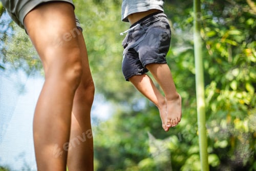 Preview: Legs of mom and her child while jumping on trampoline at backyard