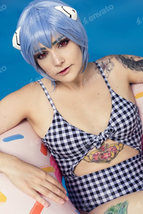 Preview: Vertical shot of a European female with blue hair on an inflatable in a pool