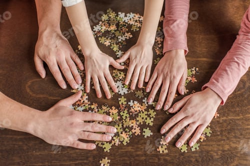 Preview: Close-up partial view of family with one child playing with puzzles on table