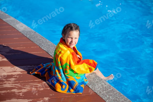 Preview: Child is sitting by pool. Little girl looks at bright sun and squints, sits on side of pool and