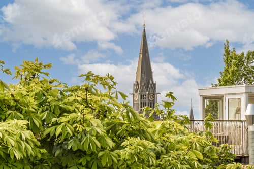Preview: a church with a tall steeple behind a garden