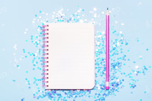 Preview: Top view of paper note book with white page and pencil on blue sparkly background.