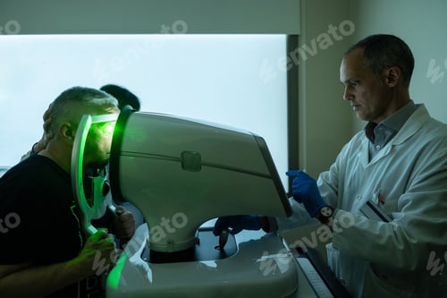 Preview: Ophthalmologist treating glaucoma on a senior man using laser machine