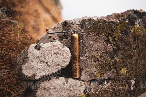 Preview: Old rustic coffee grinder between rocks in the mountains