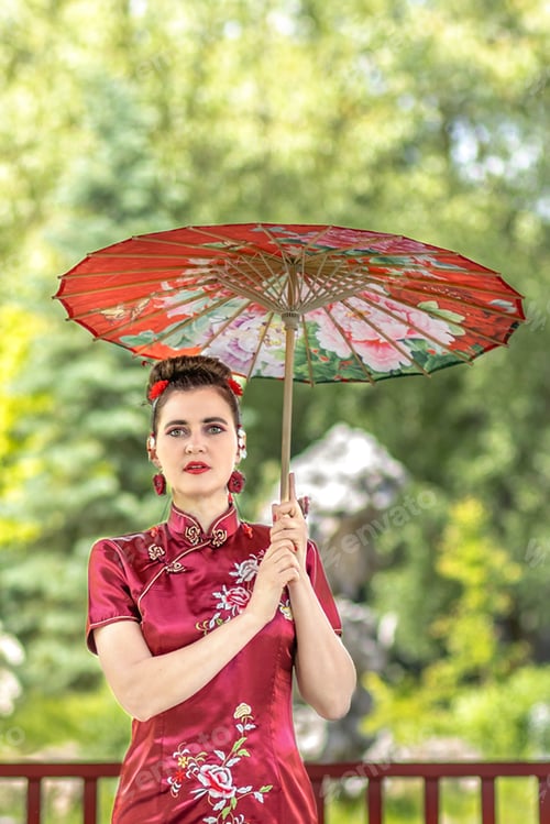Preview: A Asian girl walk in national clothes with a umbrella in the park.Chinese woman in a red traditional