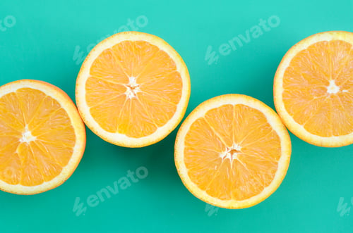 Preview: Top view of a several orange fruit slices on bright background in turquoise green color