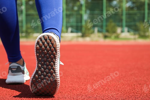 Preview: Girl walking on red athletic track, space for text