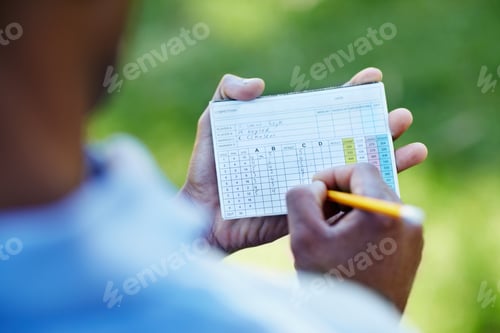 Preview: Staying below par. Rearview shot of a young golfer marking his scorecard.