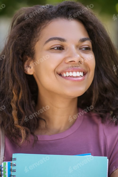Preview: A picture of a girl in a pink tshirt holding textbooks in her hands