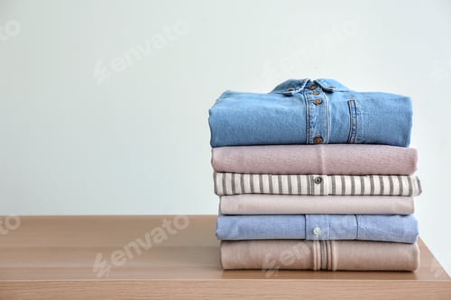 Preview: Stack of clothes on table against light background