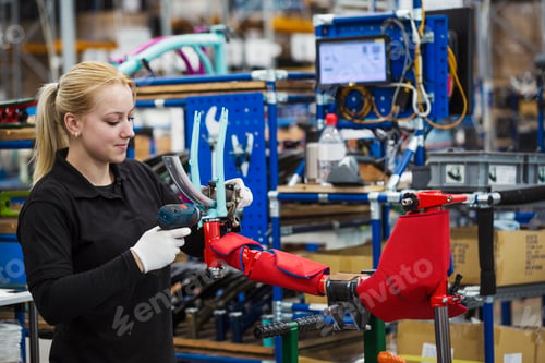 Preview: Female skilled factory worker assembling a bicycle handling the brakes assembly and part of the