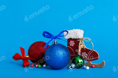 Preview: Christmas ball with skates on colored background. decoration bauble with ribbon bow with copy space