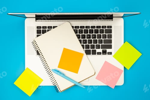 Preview: Laptop, notepad and paper reminders on blue background, flat lay.