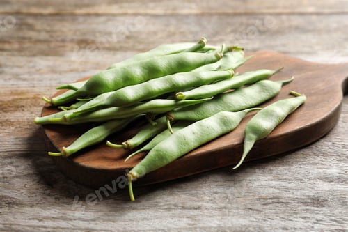 Preview: Wooden board with fresh green beans on table