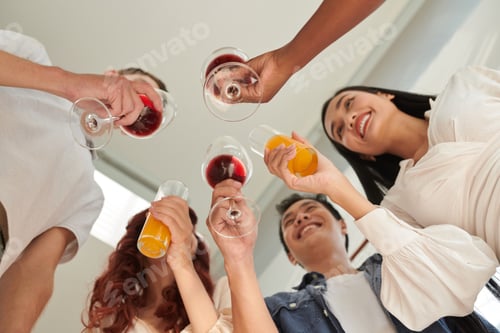 Preview: Below view of group of young people toasting with red wine and orange juice