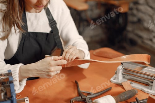 Preview: Cropped photo of female leather craftsman working on a belt