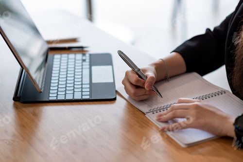 Preview: Close up of businesswoman holding a pen take notes using a tablet at the office.