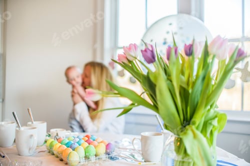 Preview: Dyed Easter eggs on table in front of mother and baby son at Easter