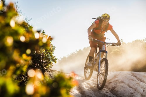 Preview: Mountain biker conquering a dusty trail at sunset