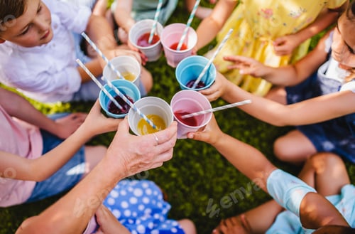 Preview: Midsection of small children sitting on ground outdoors in garden in summer, drinking.