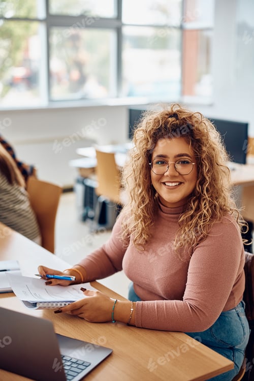 Preview: Happy female student learning in the classroom looking at camera.