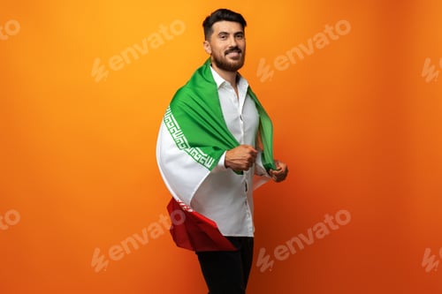 Preview: Portrait of a young casual man holding flag of Iran against orange background