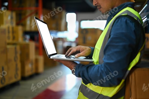 Preview: Cropped shot of male worker checking supply export shipment on laptop.