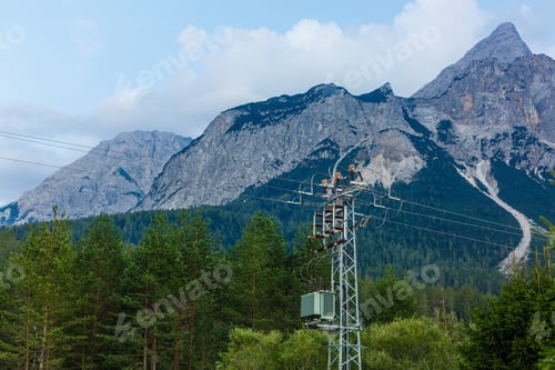 Preview: Electric poles near the mountain have green trees.