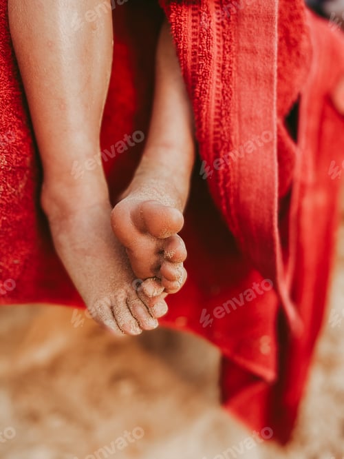 Preview: Little kid’s toes in sand and towel on the beach