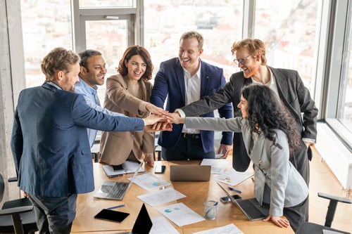Preview: Business Team Celebrating Success With Hand Stack in Modern Office