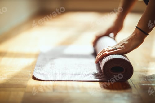 Preview: Hands Rolling Up Yoga Mat on Wooden Floor