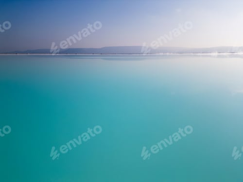 Preview: A mesmerizing turquoise lake with a soft gradient sky and a calm horizon. The serene waters and