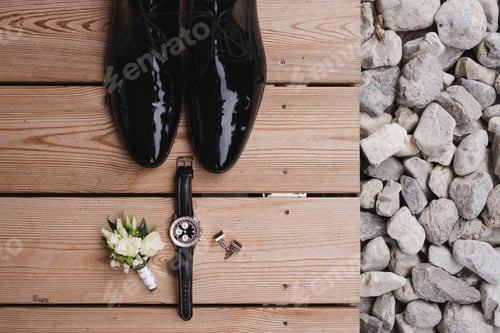 Preview: Top view of boutonniere, shoes, watch, cufflinks and tie on wooden background.