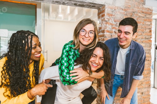 Preview: Diverse young coworkers laughing and playing in modern office