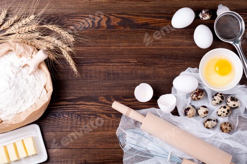 Preview: Ingredients for baking. Flour in paper bag, eggs, butter, rolling pin and whisk on wooden background