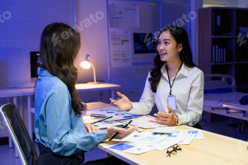 Preview: Two businesswomen working late at night reviewing marketing strategy in the office