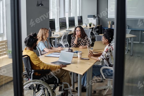 Preview: Diverse Programmers Discussing Business Affairs at Desk in Modern Urban Office