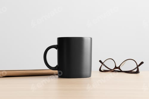 Preview: Black mug mockup with workspace accessories on the wooden table.